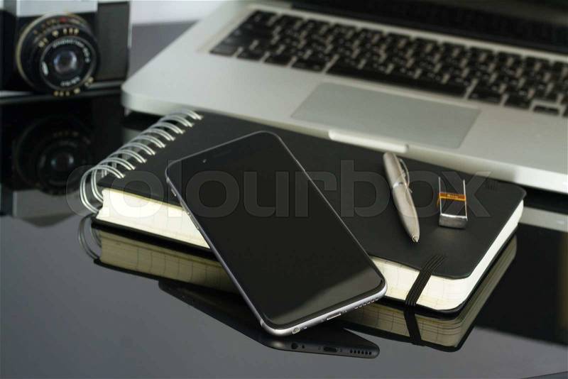 Office glass desk table with phone, laptop and supplies, stock photo