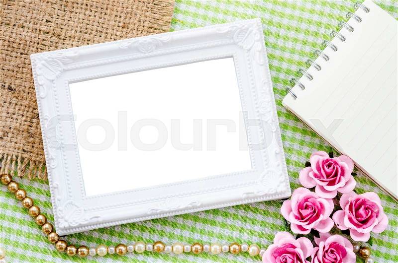 Blank vintage white photo frame and open diary with pink rose on fabric background. Save clipping path, stock photo
