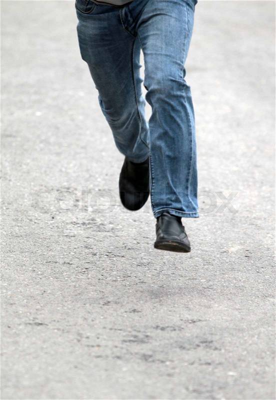 Man\'s feet in blue jeans in shoes close up, set in motion, stock photo