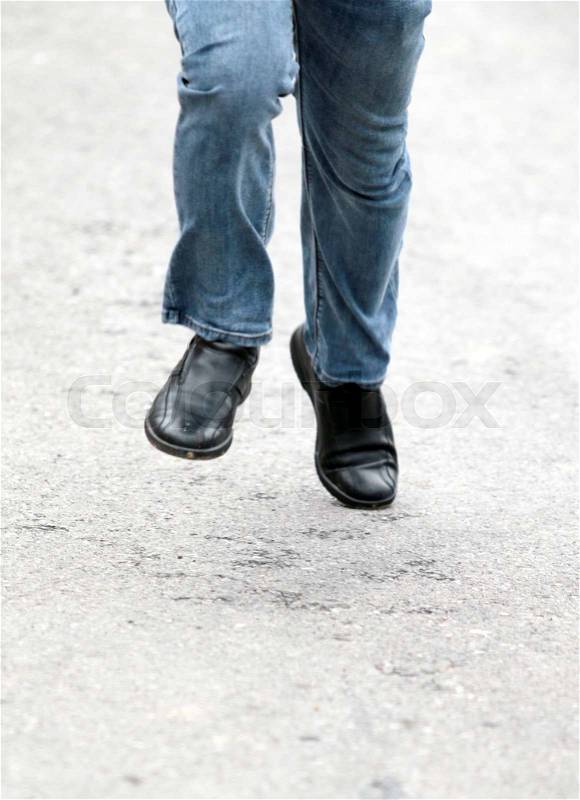 Man's feet in blue jeans in shoes close up, set in motion, stock photo