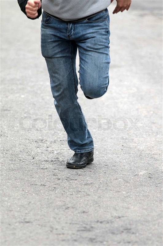 Man\'s feet in blue jeans in shoes close up, set in motion, stock photo