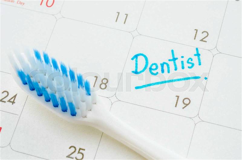 The words Dentist written on a calendar to remind you an important appointment with tooth brush, stock photo