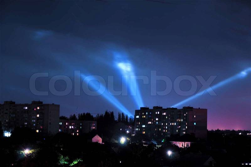 Night sky over city in lights of projectors, stock photo