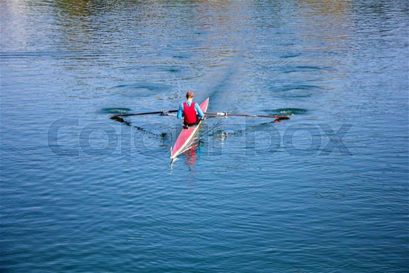 Young man Rower in a boat, rowing on the tranquil lake, stock photo