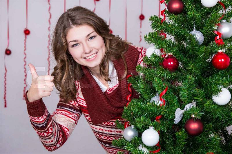 Portrait of happy young beautiful woman thumbs up with decorated Christmas tree, stock photo