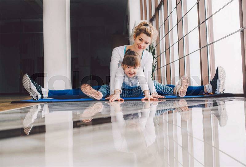 Mother and daughter hugs and stretch in the gym, stock photo