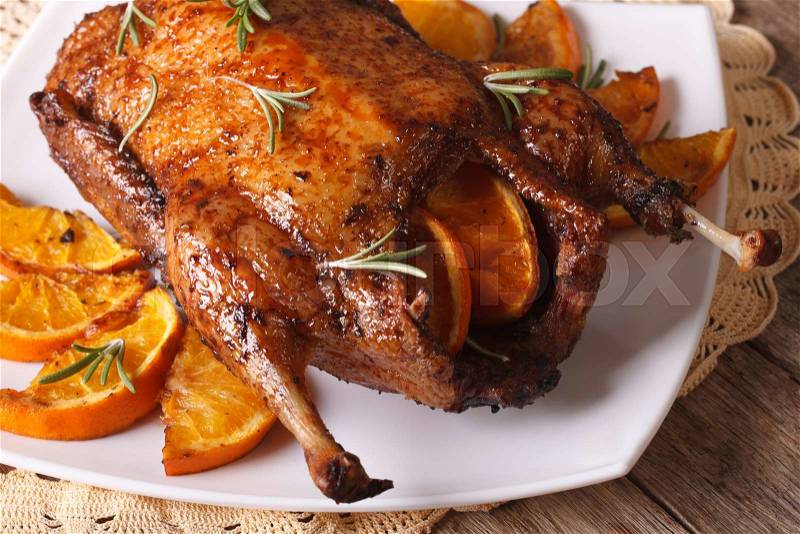 Whole roast duck with oranges and rosemary close up on a plate. horizontal , stock photo