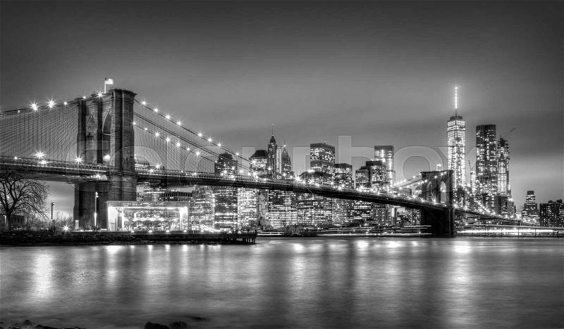 Brooklyn bridge and New York City Manhattan downtown skyline at dusk with skyscrapers illuminated over East River panorama. Copy space. Black and white image, stock photo