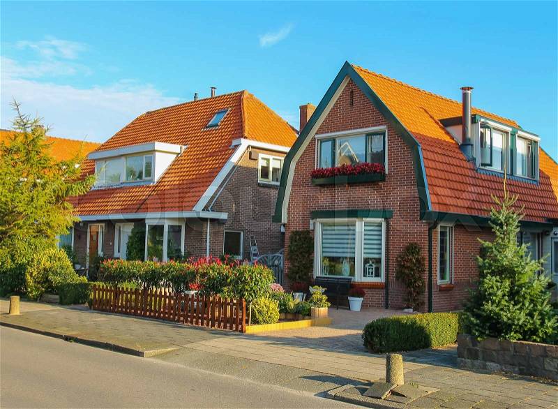 Picturesque residential houses with decorative plants before them in small Dutch town Zwanenburg, the Netherlands, stock photo