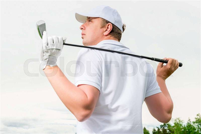 Golfer in a cap against the sky with a golf club, stock photo