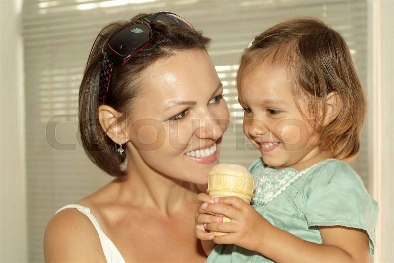 Little cute girl eating ice cream with her mother, stock photo