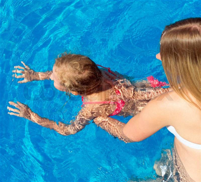 Woman teaching little girl to swim. Place for text, stock photo