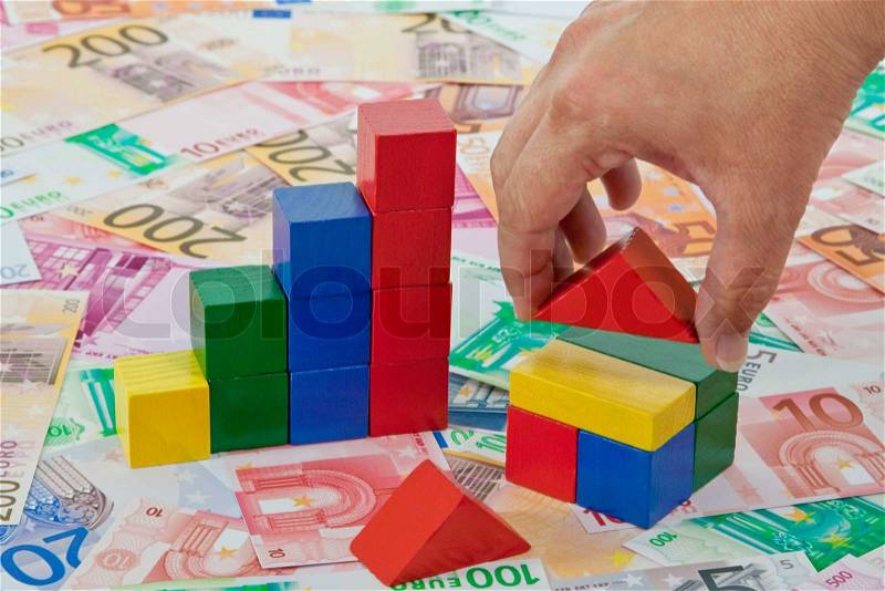 Towers and House of toy bricks on euro notes, stock photo