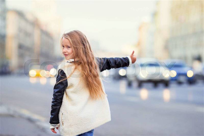 Adorable little girl get taxi outdoors in European city, stock photo