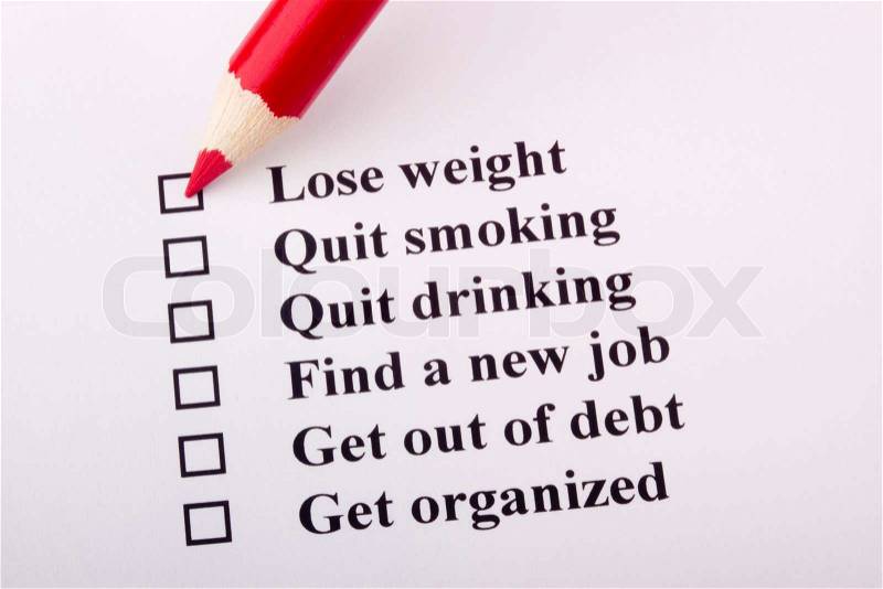 A red pencil laying on a paper with a list of goals, stock photo