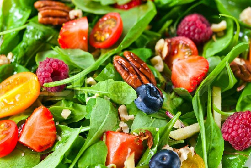 Green vegan salad with berries and nuts, stock photo