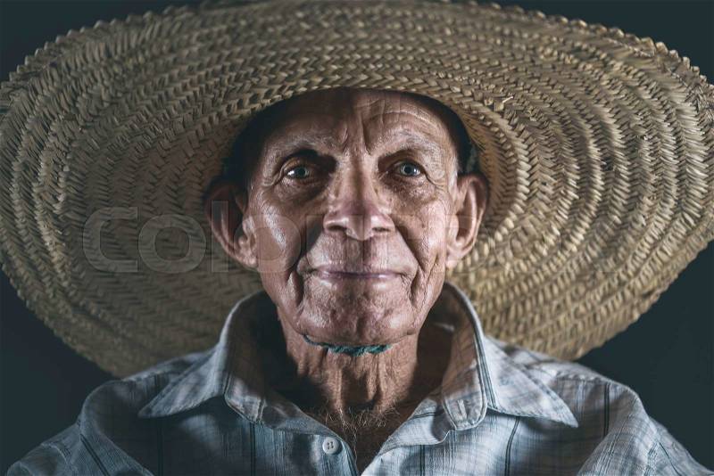 Elderly man wearing a straw hat, ready to work under the sun, stock photo