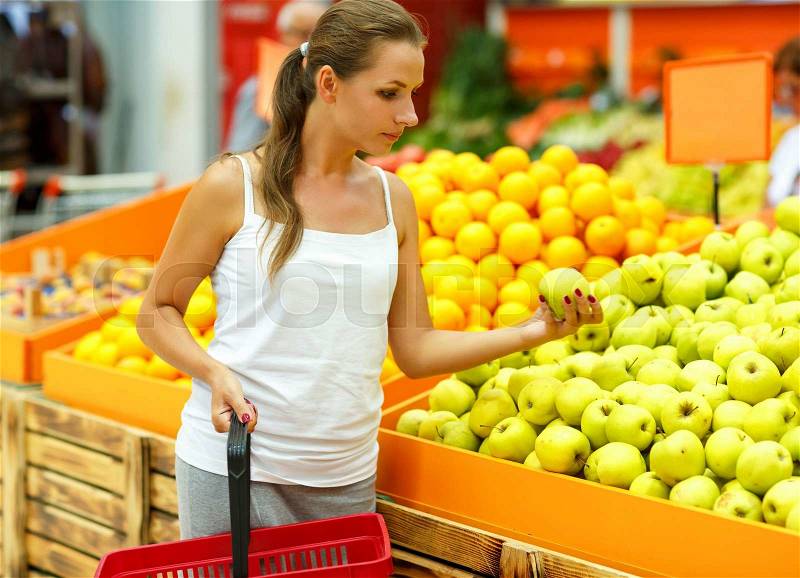 Young beautiful woman shopping in a supermarket in the department of fruit and vegetables, stock photo