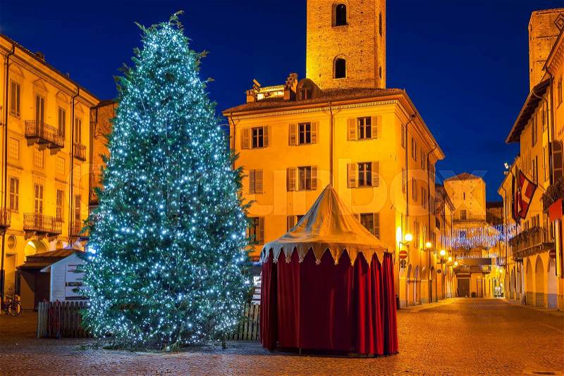 Illuminated Christmas tree on town square at evening in Alba, Piedmont, Northern Italy, stock photo