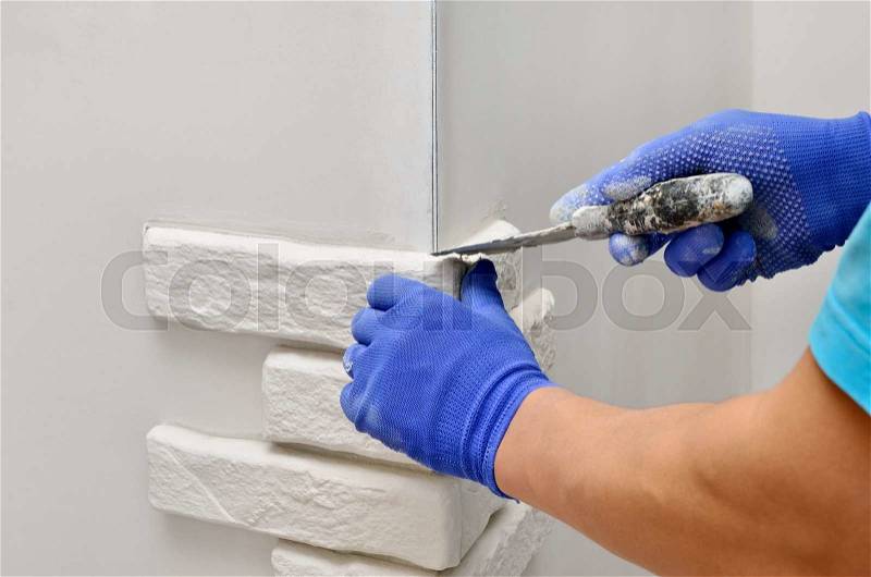 Facing wall decorative tiles, workers in blue glove, stock photo