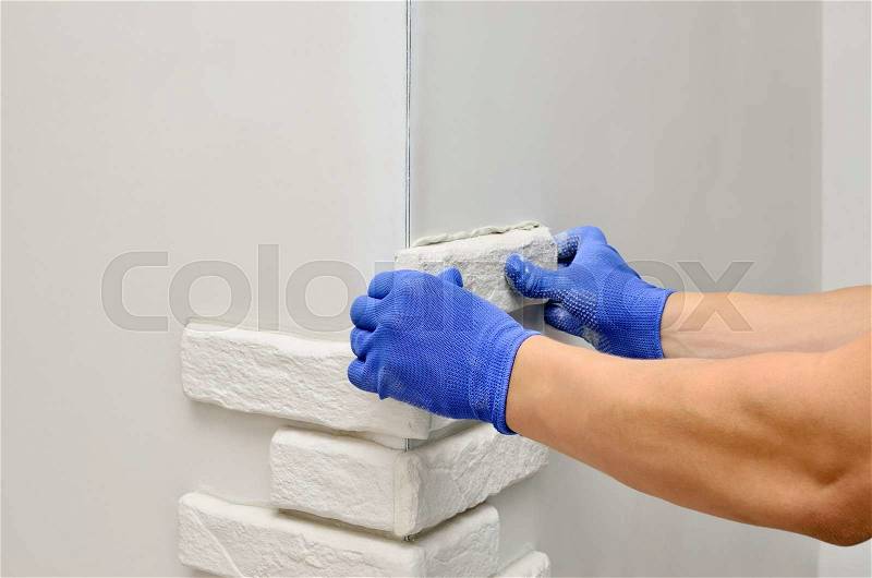 Facing wall decorative tiles, workers in blue glove, stock photo