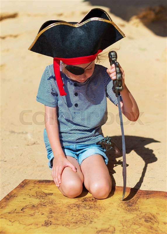 Little girl in pirate costume with sword looking on the map, stock photo