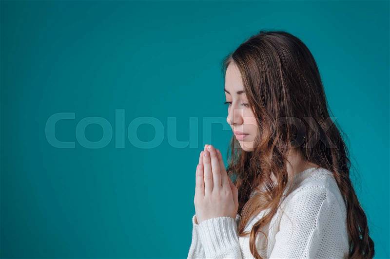 Beautiful woman in white sweater folded her hands in prayer to God, stock photo