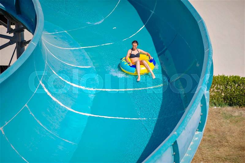 Beautiful girl riding a water slide, stock photo