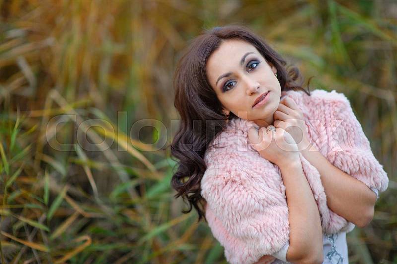 Beautiful woman in a pink cape walks in the park, stock photo