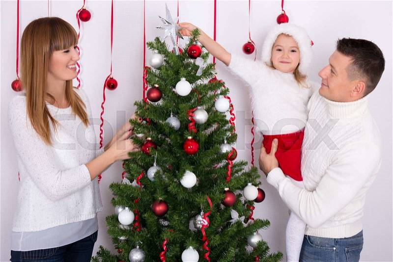 Young happy family decorating Christmas tree at home, stock photo