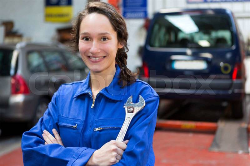 View of a Young attractive woman mechanic working at the garage, stock photo