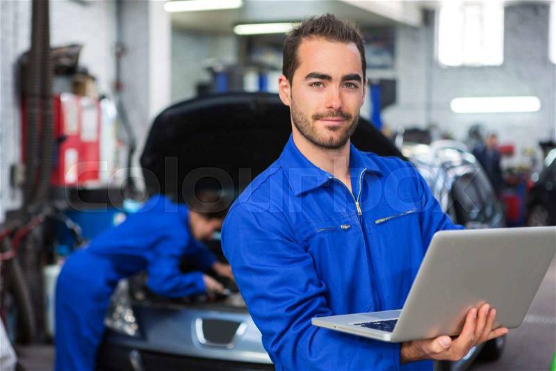 View of a Young attractive mechanic working at the garage, stock photo