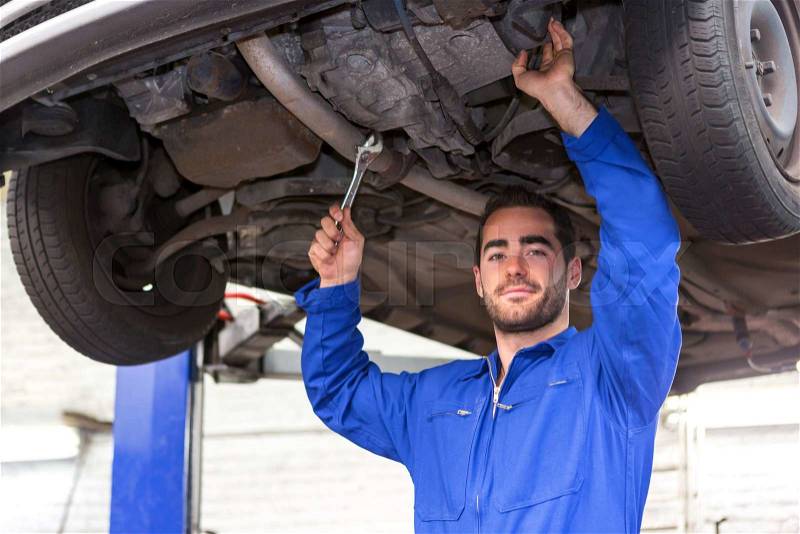 View of a Young attractive mechanic working on a car at the garage, stock photo