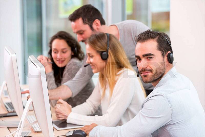 View of a Young attractive people learning their new job at call center , stock photo