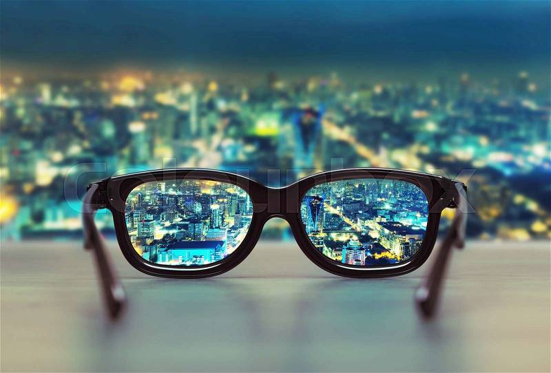 Night cityscape focused in glasses lenses. Vision concept, stock photo