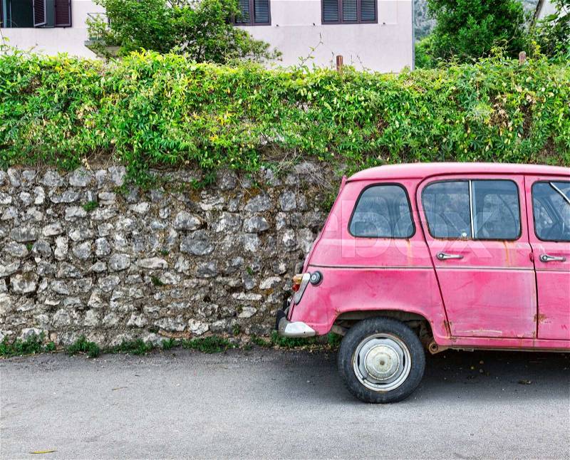 Old pink car near an old brick wall, stock photo