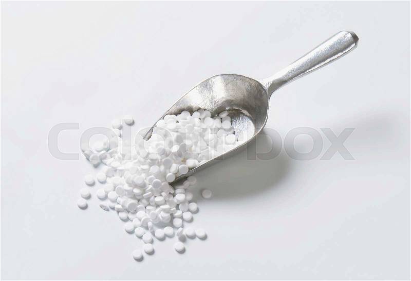 Artificial sweetener tablets in metal scoop, stock photo