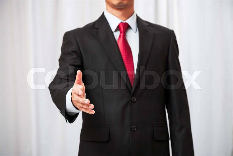 Businessman letting one hand out in a sign for a handshake, stock photo