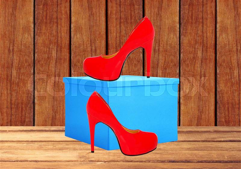 Red woman shoe and blue gift box on wooden table background, stock photo