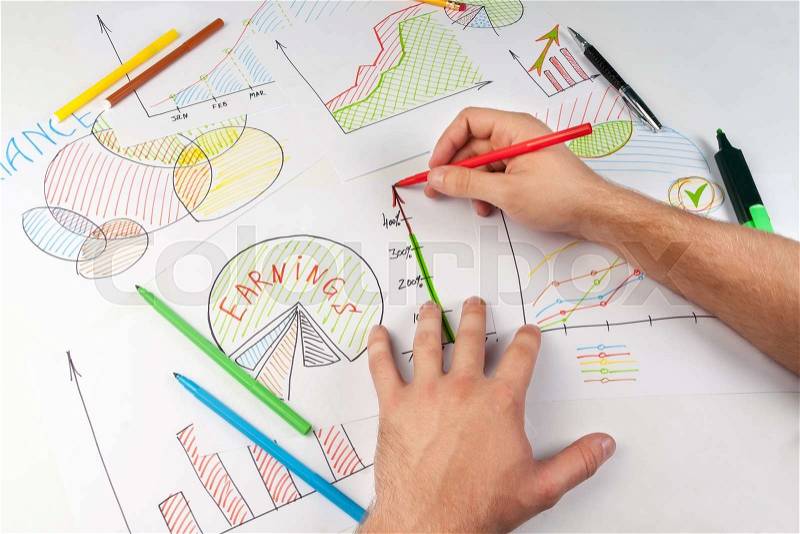 Man painting business diagrams on white papers with soft-tip pen, stock photo