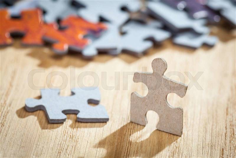 Two jigsaw puzzle pieces on a table. Shallow depth of field, stock photo