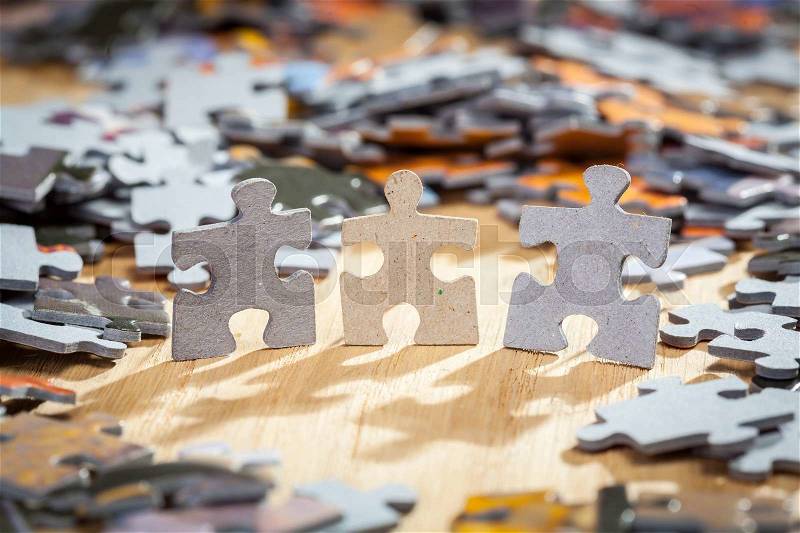 Three paper jigsaw puzzles surrounded by pieces on a table. Shallow depth of field, stock photo