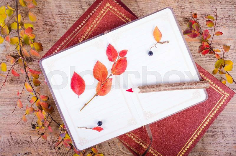 Autumn leaves, notebook, diary, pencils lying over wooden background. Fall and thanksgiving setting. Autumn composition, stock photo