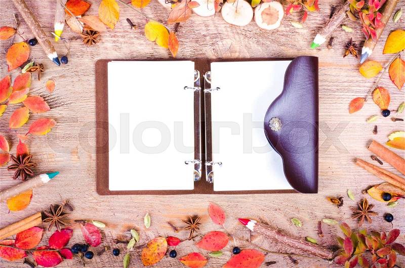 Colorful autumn leaves, spices, cinnamon, cloves, cardamom, anise and pensils lying near diary, notebook on wooden background. Fall and thanksgiving setting. Autumn composition. Free space for text, stock photo