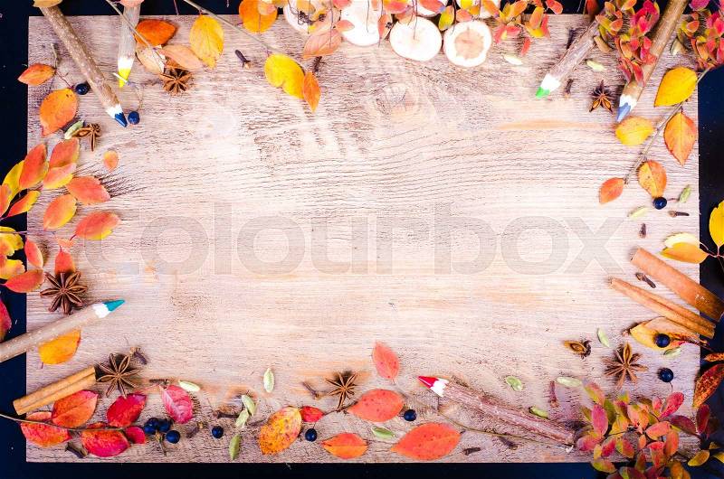 Colorful autumn leaves, spices, cinnamon, cloves, cardamom, anise and pensils lying on wooden background. Fall and thanksgiving setting. Autumn composition. Free space for text, stock photo