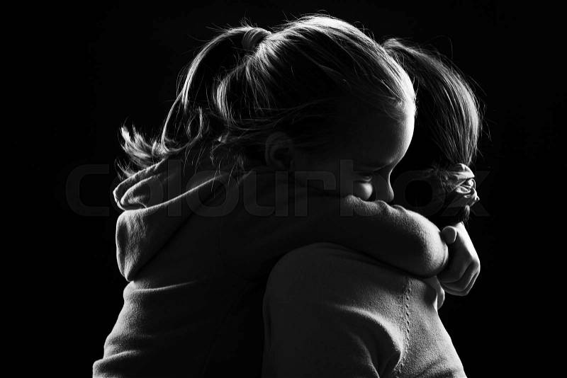 Black and white image of a little girl hugging her mother, stock photo