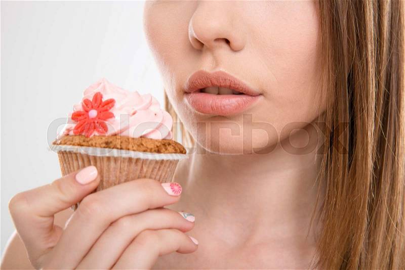 Pretty sensual attractive woman trying to eat a cupcake, stock photo