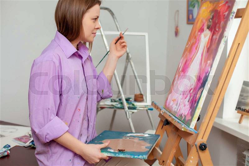 Creative female artist drawing the picture in the studio, stock photo