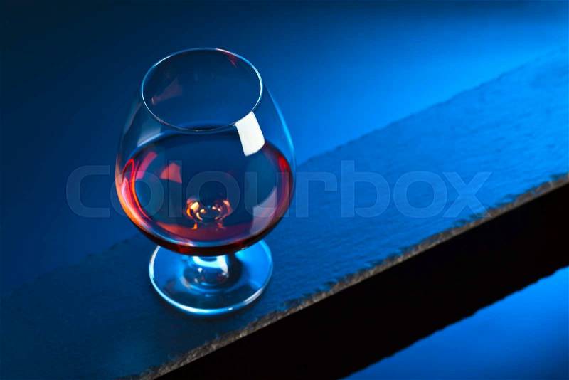 Snifter with brandy on a blue background, stock photo