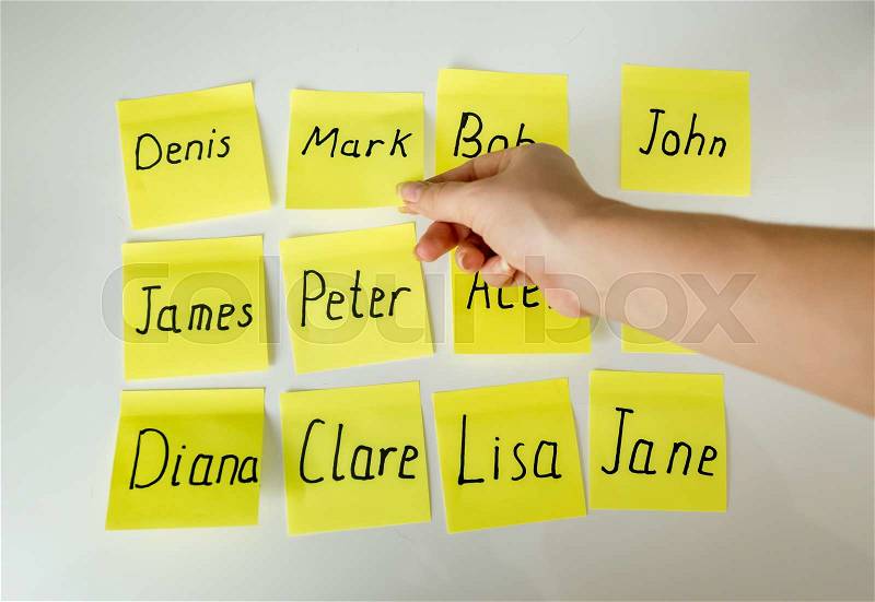 Conceptual photo of hard choice of baby\'s name. Hand picking papers with names, stock photo